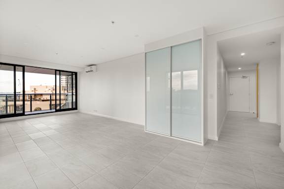 A large empty room with a glass door and a sliding door.