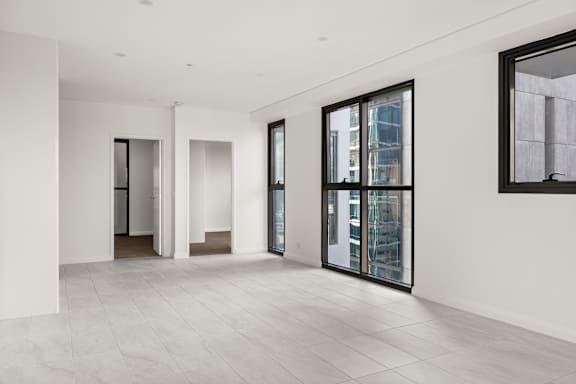 A spacious room with a large window and a painting on the wall.