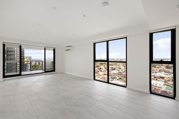 A large empty room with a view of the city through the windows.