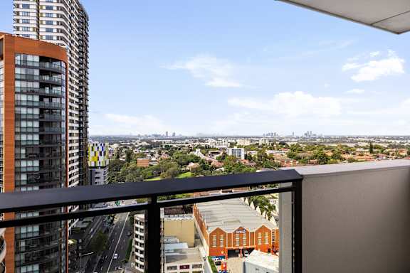 A view from a balcony overlooking a cityscape with buildings and a highway.