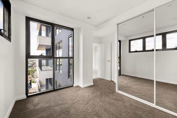 A room with a carpet floor and a large mirror on the wall.