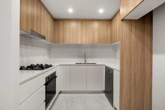 A modern kitchen with wooden cabinets and a black stove top.