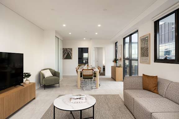 A modern living room with a grey sofa, a white coffee table, and a flat screen TV.