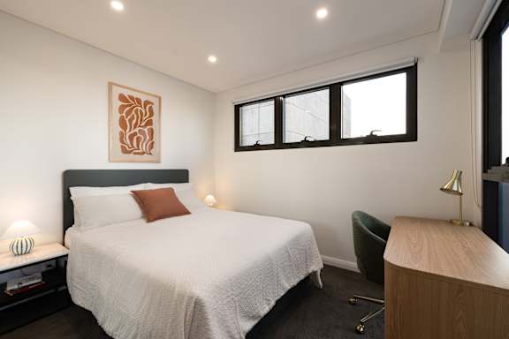 A bedroom with a large bed and a green chair.