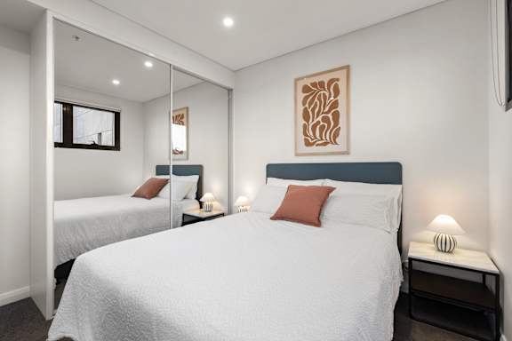 A bedroom with two beds, one with a red pillow.