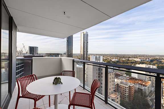 A balcony with a table and chairs overlooking a cityscape.