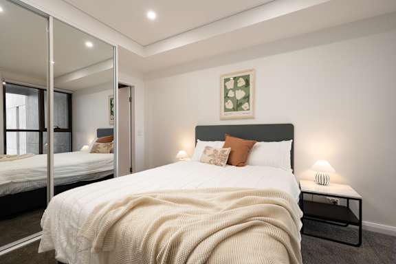 A bedroom with a large bed and a mirrored wardrobe.