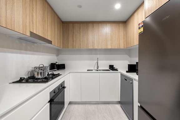 A modern kitchen with a stainless steel refrigerator and wooden cabinets.