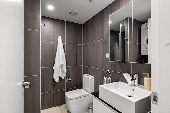 A modern bathroom with a toilet, sink, and mirror.