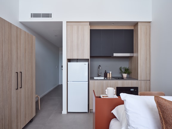 a bedroom with a bed and a kitchen with a refrigerator