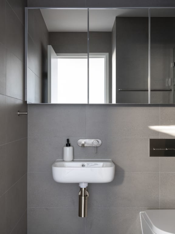 a small white sink in a bathroom under a mirror