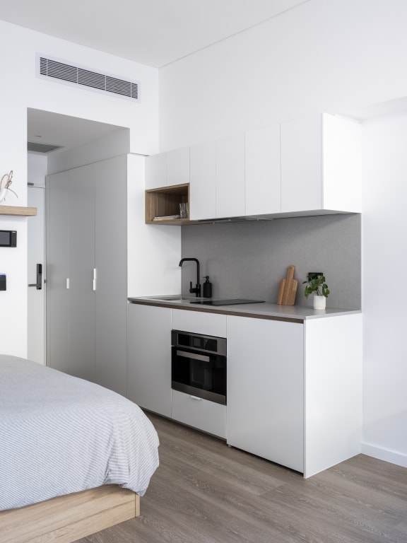 a bedroom with a bed and a kitchen with white cabinets