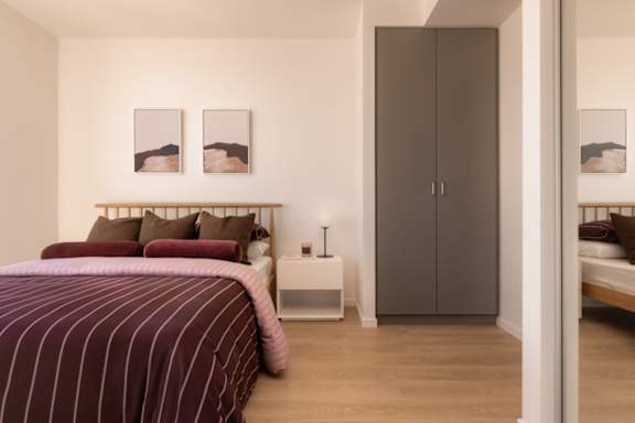 A bedroom with a bed, nightstand, and two framed pictures on the wall.