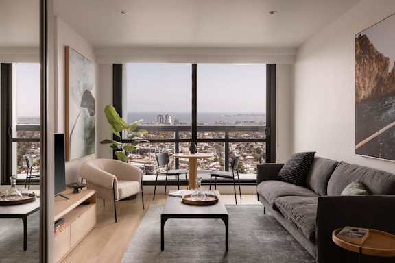 A living room with a grey couch and a view of the city.