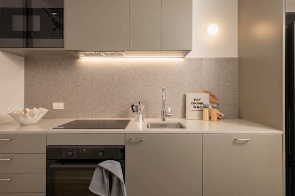A modern kitchen with a microwave, oven, and sink.