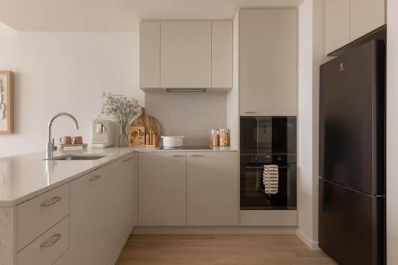 A modern kitchen with a black refrigerator and white cabinets.