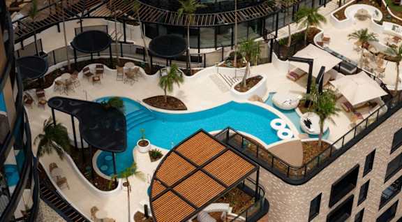 A rooftop pool area with a slide and lounging areas.