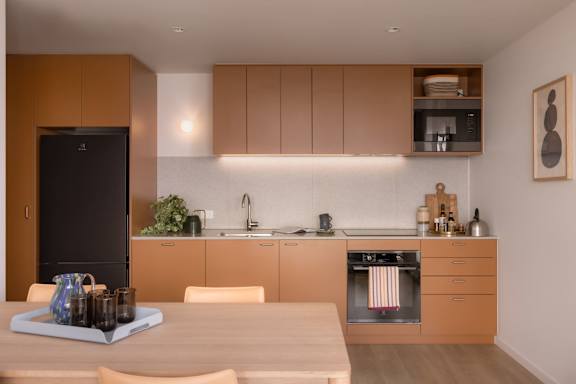 A modern kitchen with wooden cabinets and a black fridge.
