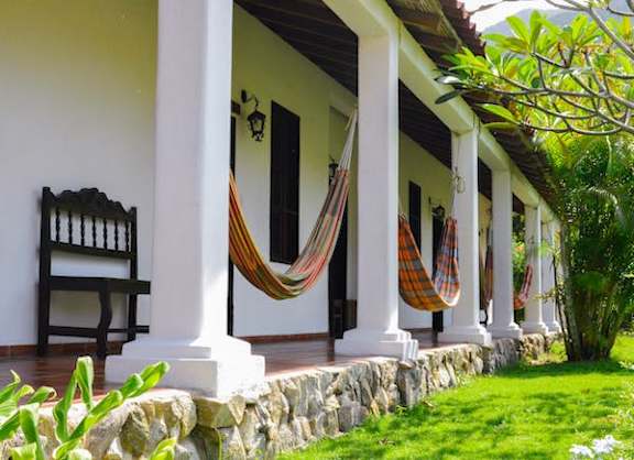 a porch with hammocks and chairs outside of a house