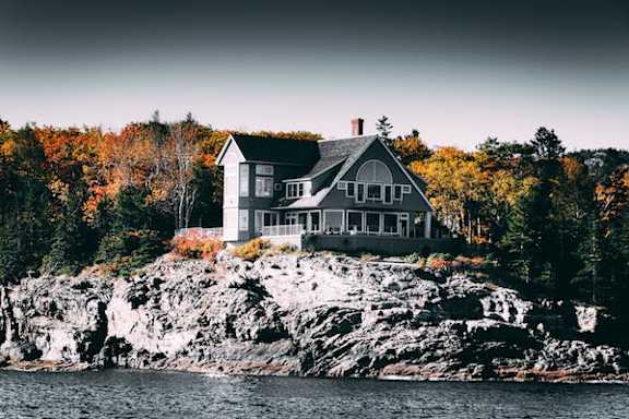 a house sitting on a rock on the water