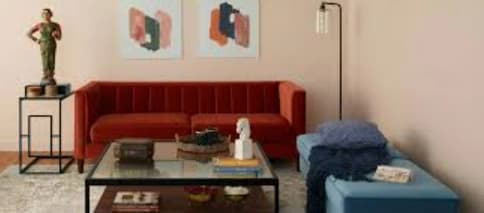 A living room with a red couch, a glass coffee table, and a statue on a small table.