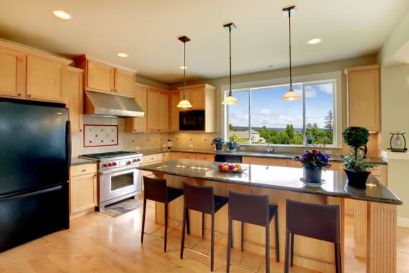 a kitchen with wooden cabinetry and a large center island with a black countertop