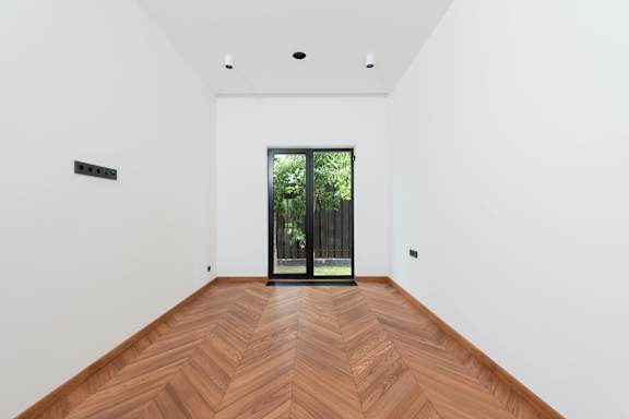 A room with a wooden floor and a glass door leading outside.