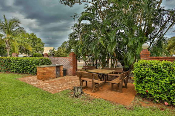 A patio with a table and chairs surrounded by greenery.