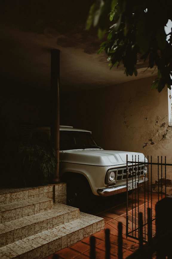 A white vintage car is parked on a staircase.