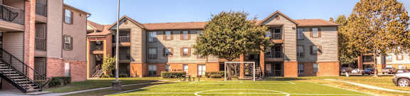 A large apartment complex with a soccer goal in the front yard.