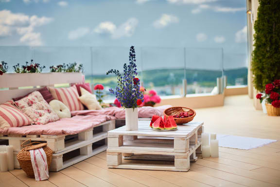 a barhftuylcony with couches and a table with flowers