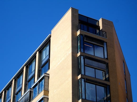 A tall building with many windows and a blue sky in the background.
