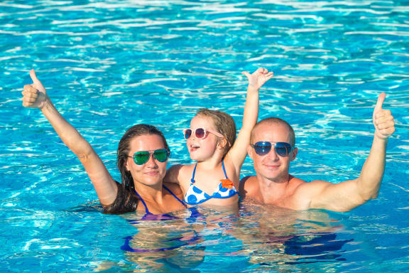 a man and two women in a swimming pool with their thumbs up