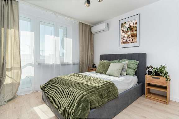 A bedroom with a large bed and a plant on the side table.