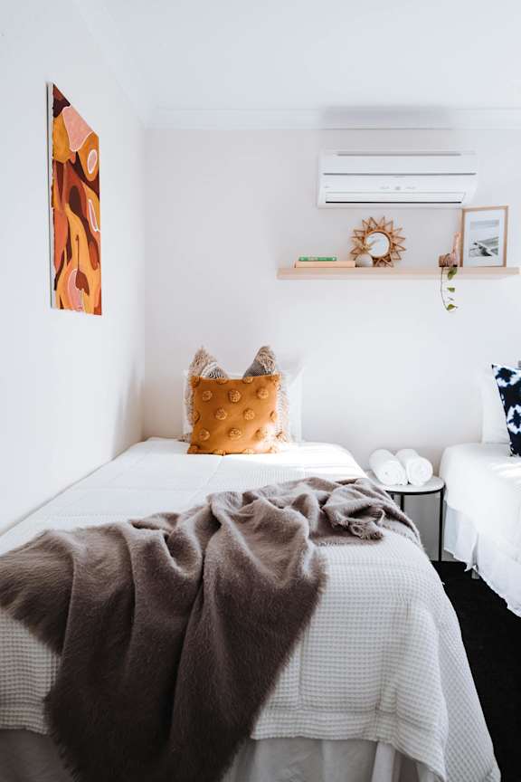 A bed with a white comforter and a brown blanket is in the foreground.