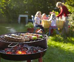 a barbecue grill with food on it and people in the background