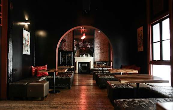 A dark room with a fireplace and a large arched doorway.