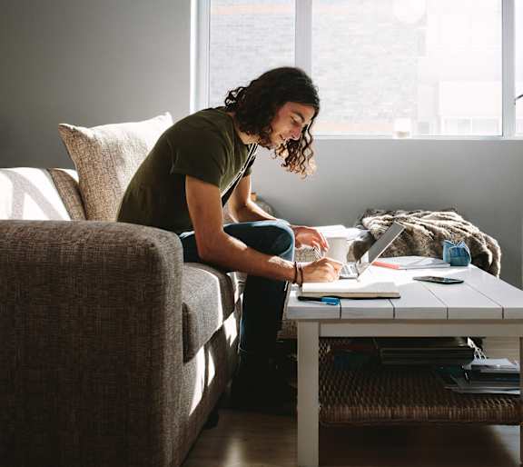 a woman sitting on a couch working on her laptop