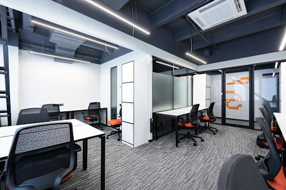 A modern office space with black chairs and white desks.