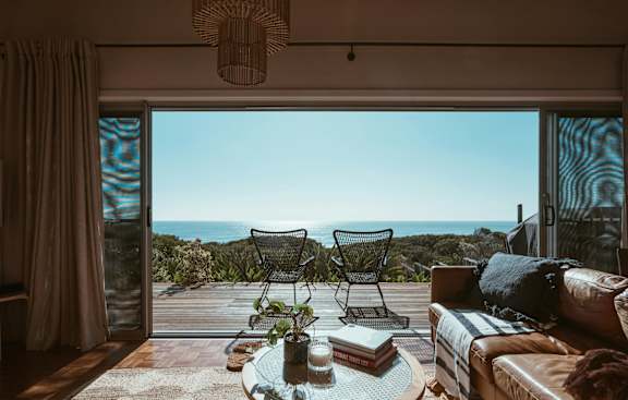 A living room with a view of the ocean through the sliding glass doors.