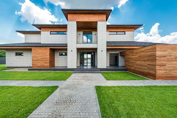 A modern house with a wooden facade and a stone pathway leading to the entrance.