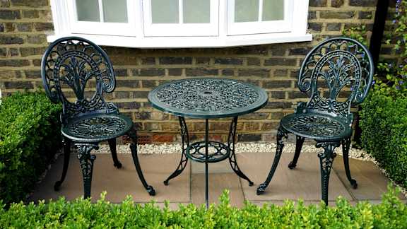 A table and two chairs are set in a garden.
