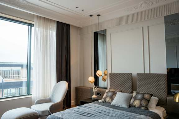 A bedroom with a large bed and a chair by the window.