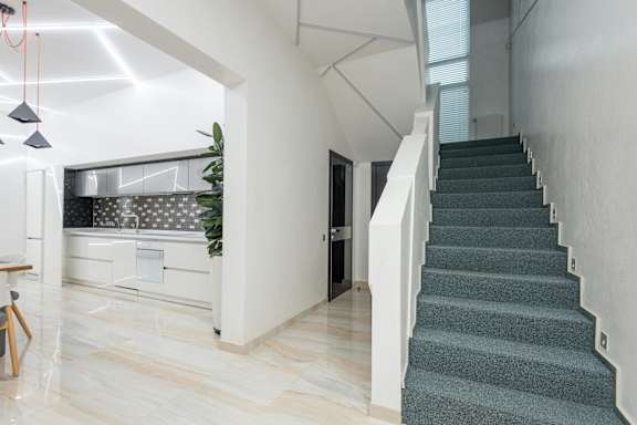 A staircase with a grey carpeted runner and white handrails.