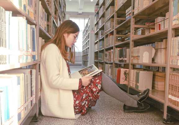 A woman is reading a book in a library.