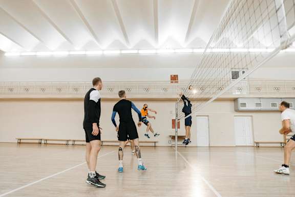 A group of people playing volleyball in a gym.