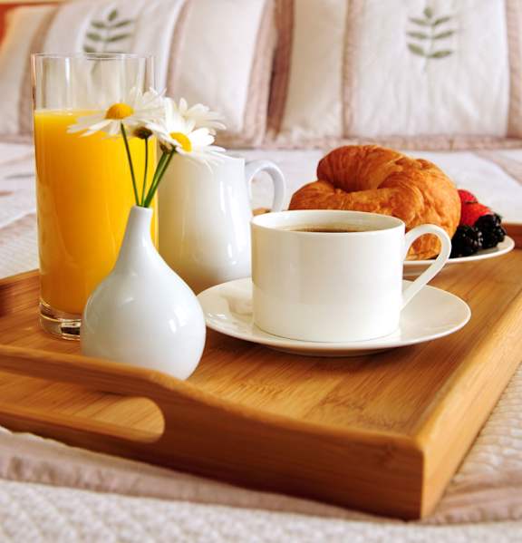 A breakfast tray with coffee, croissants, and orange juice.
