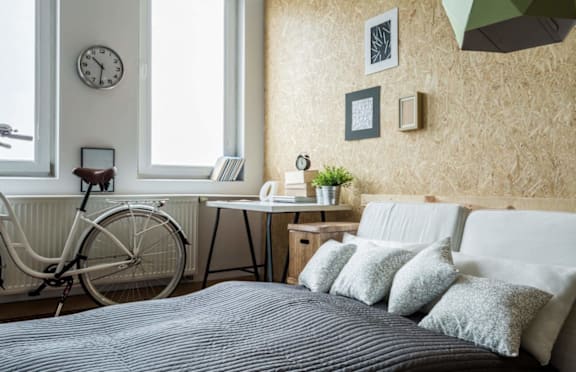 A bedroom with a bed, desk, and a bicycle.