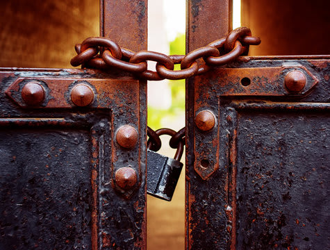 A rusty metal gate with a padlock and chain.