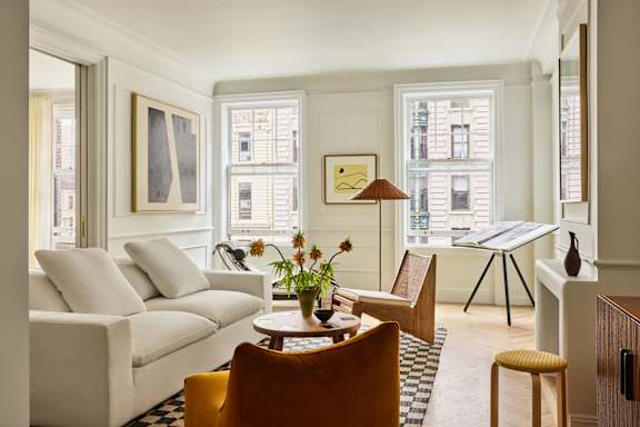 A living room with a white couch, a wooden table, and a yellow chair.